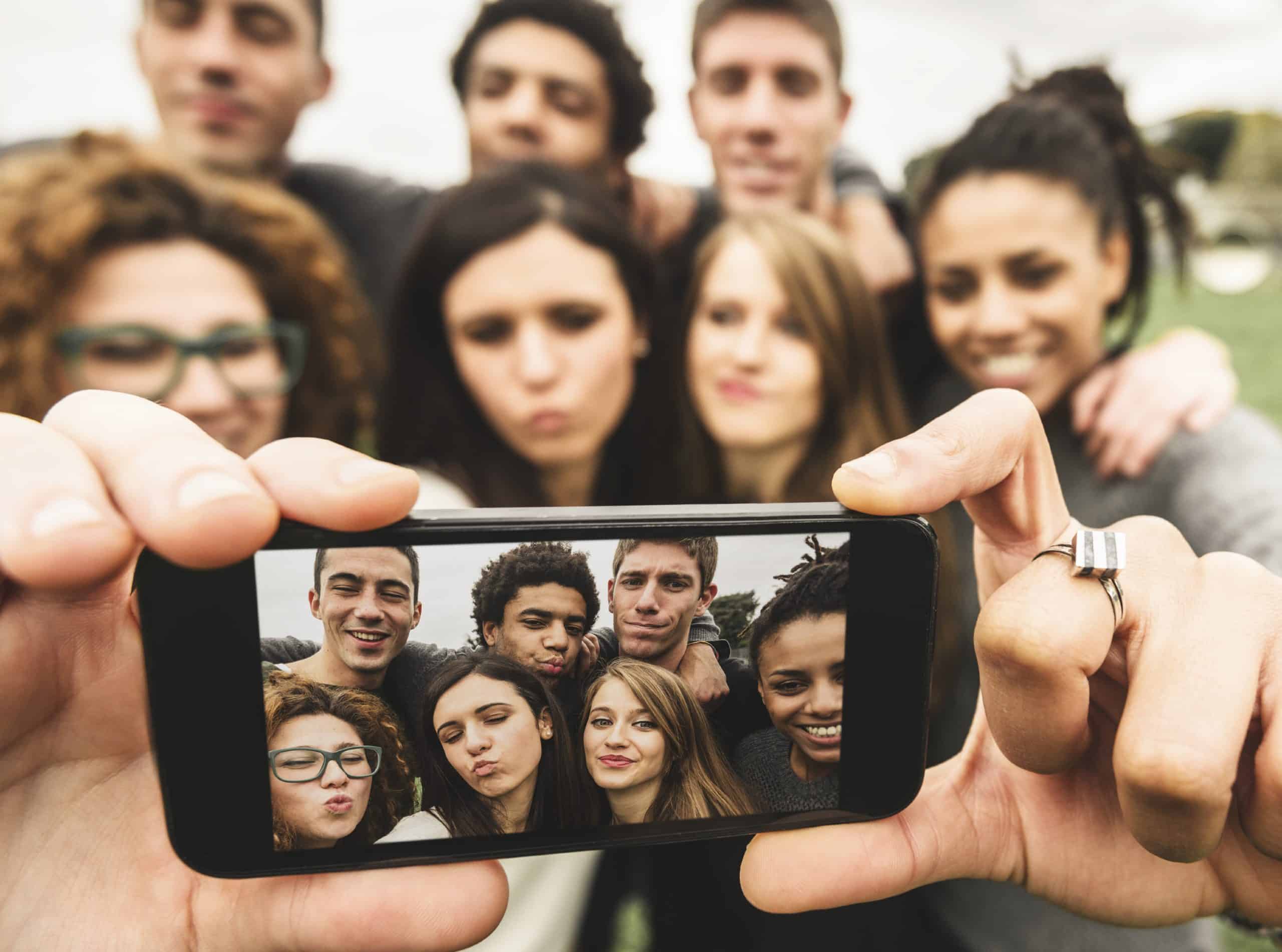 A millennial takes a selfie with other millennials.
